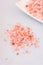 Pink Himalayan salt spilled on white table, spa, wellness, health concept