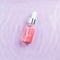 Pink hyaluronic acid serum for face with rose oils in water, top view. Regenerating, hydrating, revitalizing, detoxifying rose oil