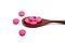 Pink ibuprofen pills in wooden spoon