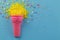 Pink icecream cone on blue background with yellow sprinkles and multicolored stars