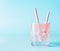 Pink iced refreshment drink in glass with paper drink straw on blue background. Copy space. Summer pastel pink cocktail