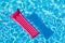 Pink inflatable mattress floating on water surface