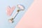 Pink jade roller and gua sha tool on pastel background