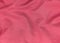 Pink jersey fabric matte texture top view. Red coral knitwear satin background. Fashion color feminine clothes trend