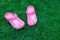 Pink kid`s slippers on green lawn. Copy space. Top view, located at side of frame. Horizontal. Concept of unity with nature.