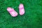 Pink kid`s slippers on green lawn. Copy space. Top view, located at side of frame. Horizontal. Concept of unity with nature.