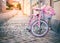 Pink kids bicycle with shopping basket stand near the wall on the street, sunlight on the background, horizontal