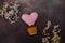 pink knitted heart in a brown knitted pot with small, multi-colored dried flowers on a dark background