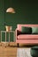 Pink lamp above cute coffee table with champagne and glasses next to couch with emerald pillows