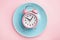 Pink larm clock on empty blue plate. Concept of intermittent fasting, lunchtime, diet