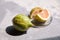 Pink lemon or Variegated Eureka lemon in glass saucer on concrete table. Citrus fruit with striped rind. Lemon pink flesh