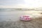 A pink life ring on the beach by the sea.