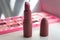 Pink lipstick tube with eye shadow palette on background. Rose lipstick on bathroom table. Decorative cosmetics. Beauty concept.