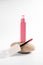 Pink liquid lipstick and applicator brush with open tube. Makeup cosmetic product. Bright background