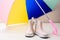 Pink little children rubber boots stand under colorful umbrella.