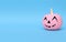 Pink little pumpkin with smile on a pastel blue background. Minimalist halloween concept.