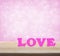 Pink love word on wooden table over light pink heart blur background, valentine concept