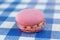 Pink macaron sitting on a blue check pattern