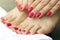 Pink manicure and pedicure on female hands and legs, close-up, side view