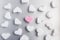 Pink marshmallow heart lies among white sugar marshmallows in the shape of hearts evenly laid out on a gray aluminum background