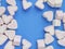 Pink marshmallow in heart shape stacked on trendy blue background with copy space. Sweet candy for love theme on Valentine concept