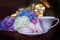 Pink marshmallow on a white saucer with multicolored hydrangea flowers and a cup