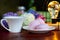 Pink marshmallow on a white saucer with multicolored hydrangea flowers and a cup