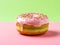 Pink matcha donut with pistachio cream on trendy green pink background. Homemade matcha doughnut covered with shiny pink matcha