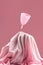 A pink medical grade silicone menstrual cup levitates over the top of a silk-covered podium.