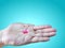 Pink Medication Pill on Hand Isolated on Cyan Background