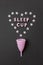 Pink menstrual cup on black background with with heart and words Sleep cup. Concept possibility of use cup at night, zero waste,