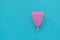 Pink menstrual cup on blue background. Female intimate hygiene concept. Top view