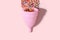 Pink menstrual cup and bright beads like blood drop with shadow on pink background. Women`s health, alternative hygiene and