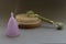 Pink menstrual cup, brush for dry massage of problem areas of the body with on top jade face roller for beauty facial massage ther