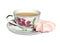 Pink meringue cake, white cup of green tea and saucer with a picture of pink flowers on white background