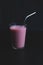 Pink milkshake with a metal straw on a black background