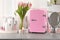 Pink mini cosmetics refrigerator and skin care products on table