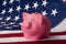 Pink moneybox pig stands on the American flag