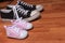 Pink newborn shoes and pair of adult sneakers