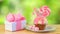 Pink novelty cupcake decorated with candy and lollipop against garden background