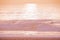 Pink Ocean Landscape in Sunset Time Background with Sandy Beach and Wavy Sea. Surfers on the water looking at waves at