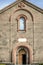 Pink openwork arches over the front door, over window and patterned cross on the facade of the Church of St. Mesrop Mashtots in Os