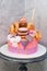 Pink and orange birthday cake decorated with macaroons, meringues, donuts, waffle cones, cake pops and chocolate bars.