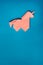 Pink origami unicorn on blue background