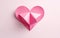 Pink paper heart isolated on pink background. Adorable origami decoration.