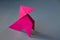 Pink paper hen origami isolated on a grey background