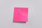 Pink paper note attached with safety pin to white background, top view