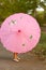 Pink parasol with little girl\'s legs and feet showing from behind