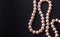 Pink pearl luxury necklace with beautiful nacreous real oyster pearl beads isolated on black background with copy space