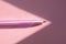 Pink pen on pastel pink background in cone-shaped natural sunlight stream, shadow and light concept, contrast. Copy space, flat